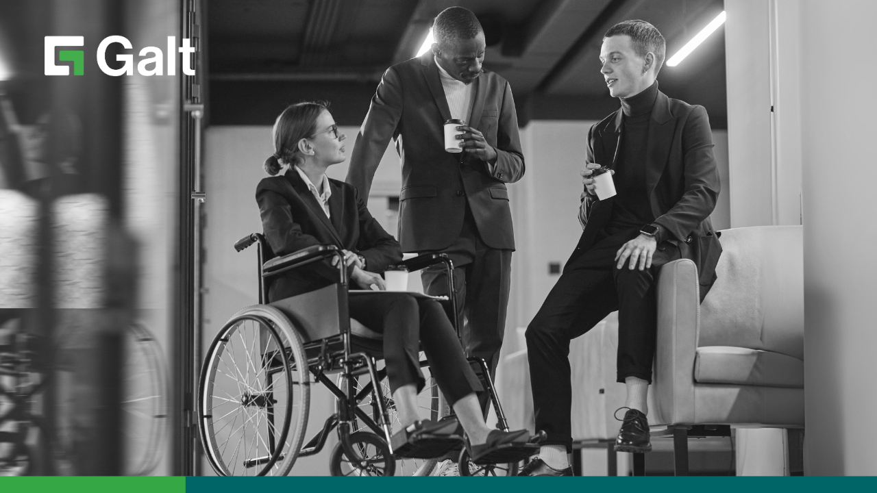 In an office setting, three colleagues engage in a discussion where one is seated in a wheelchair, another stands with a coffee cup, while the third perches on the arm of a couch; the Galt logo is at the upper left corner.